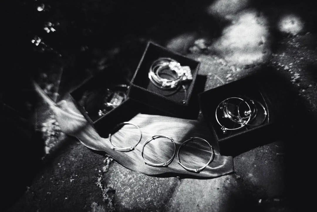 Wedding rings displayed in dark boxes beside ceremonial jewellery
