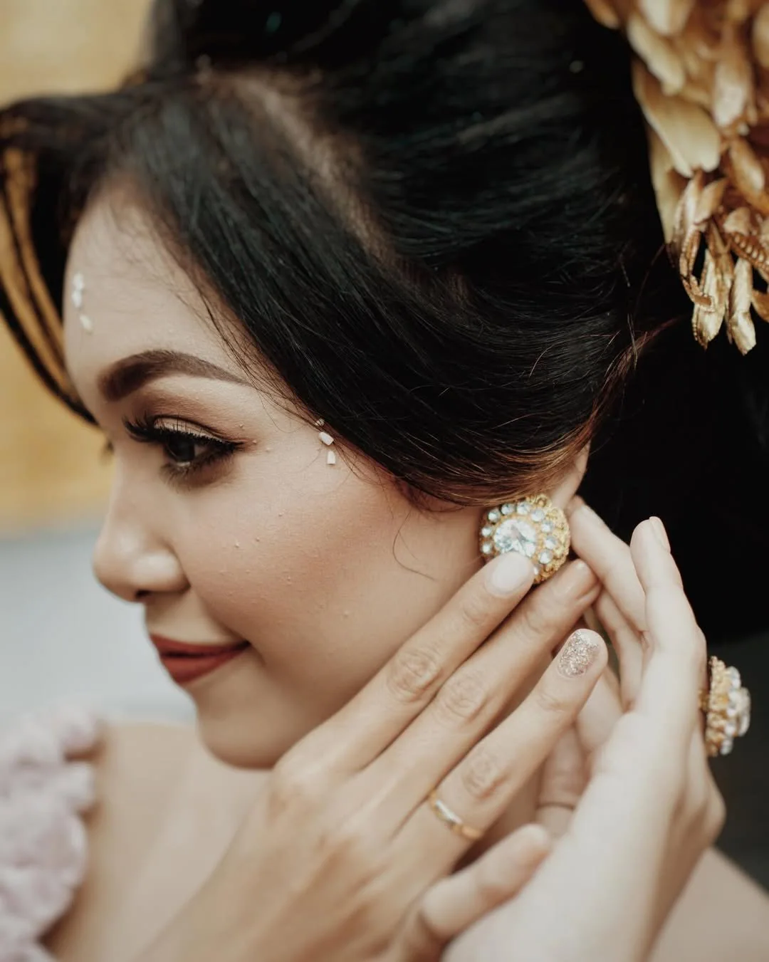 Close-up of a bride wearing gold earrings and floral hair ornaments