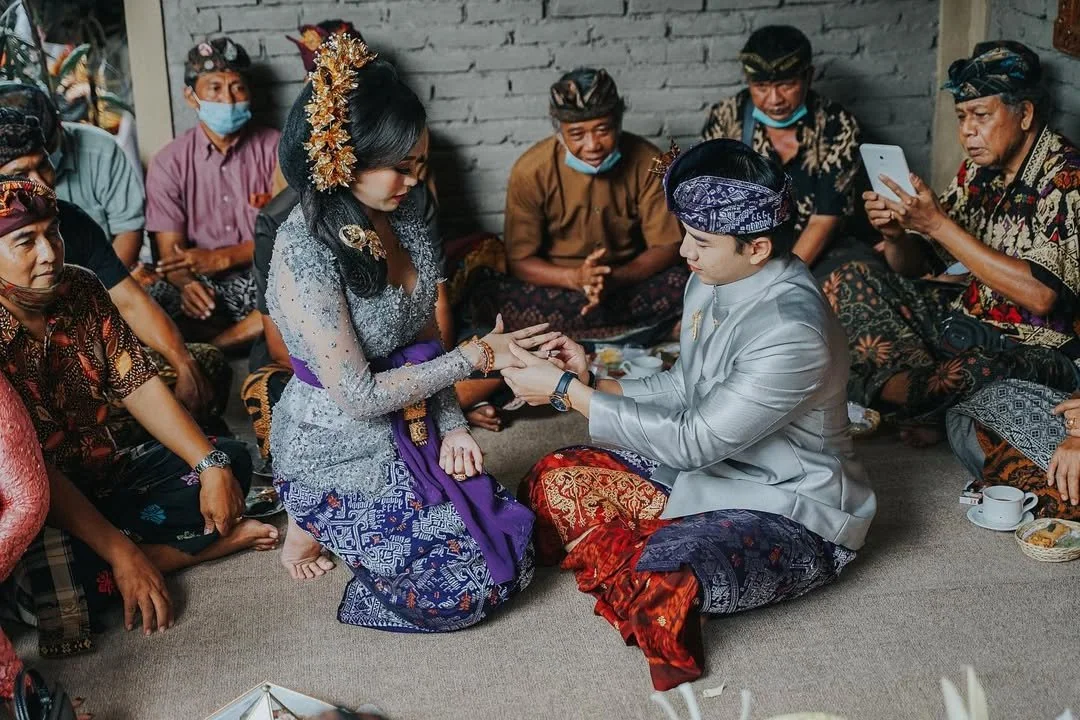 Groom seated among relatives during a Balinese wedding ritual