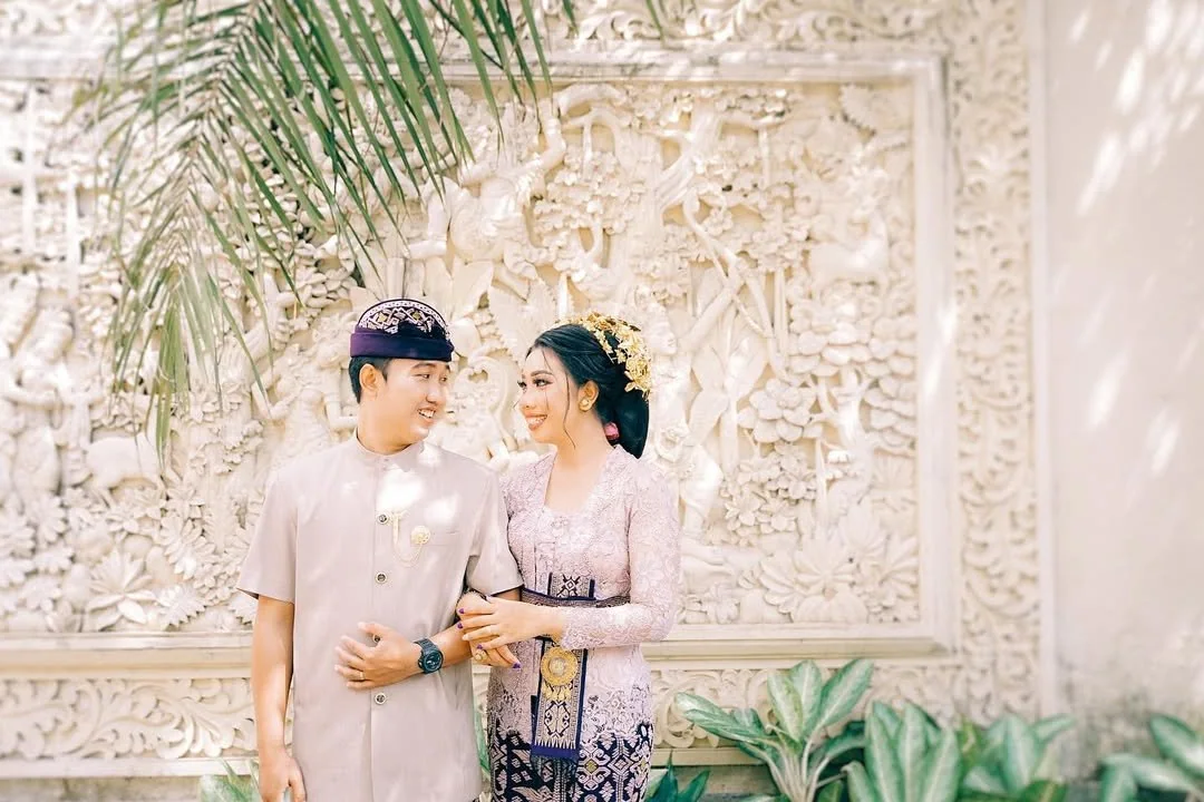 Newlyweds in matching lavender outfits beneath a carved wedding backdrop