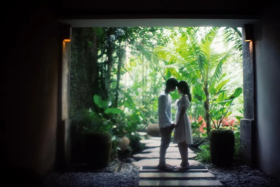 Newlyweds embracing in a shaded doorway overlooking tropical greenery