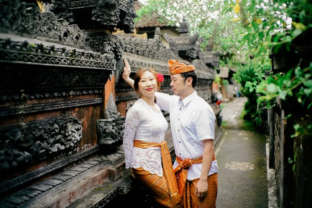 Couple in traditional Balinese attire at an ornate temple entrance
