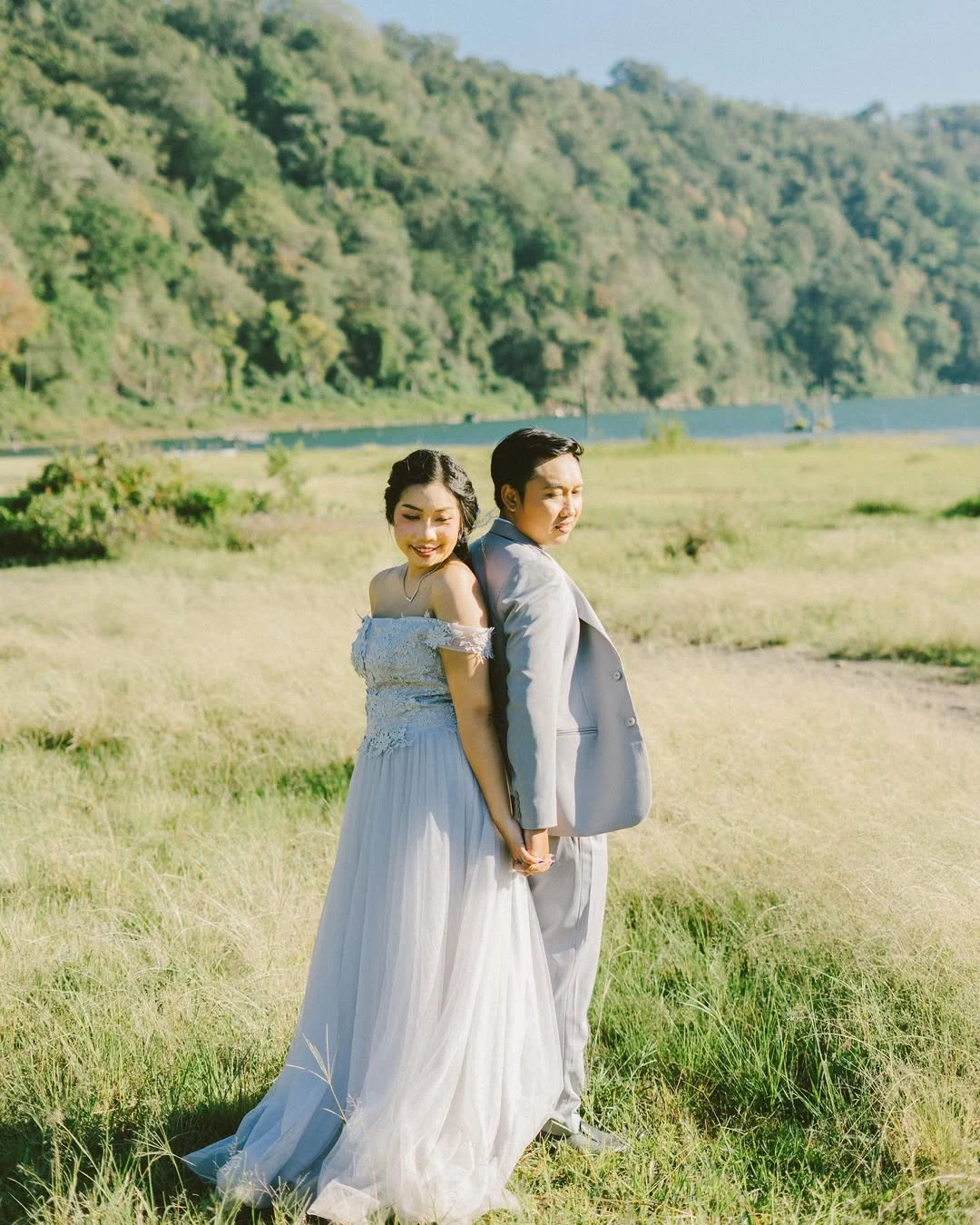 Newlyweds standing together in a quiet green field in Bali