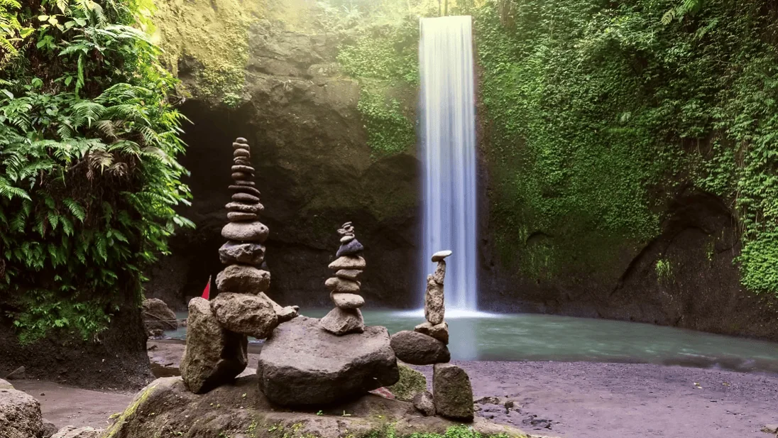 Beautiful waterfall cascading into a jungle pool surrounded by lush tropical greenery in Bali.
