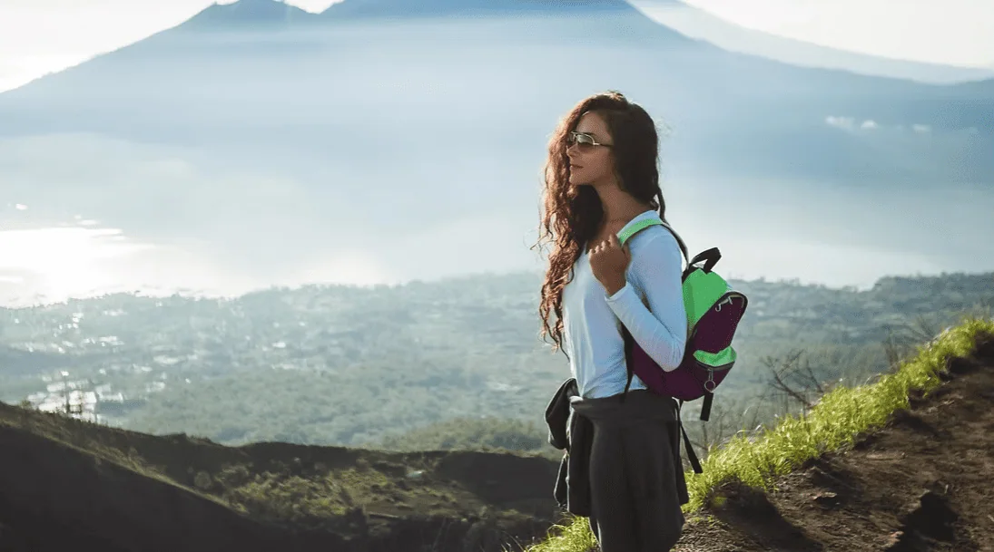 Breathtaking mountain hiking scene with woman carrying a backpack enjoying panoramic Bali views.